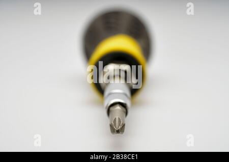 Selective focus view of a yellow and black cross head screw driver with the focus on the bit. plain white background Stock Photo