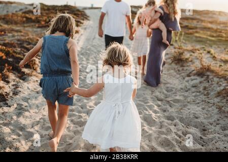 Young preschool aged girl holding hands iwth sister and walking away