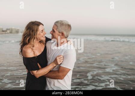 Side view of married couple looking at each other in ocean Stock Photo