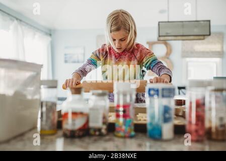 Young girl using a rolling pin to bake cookies in the kitchen