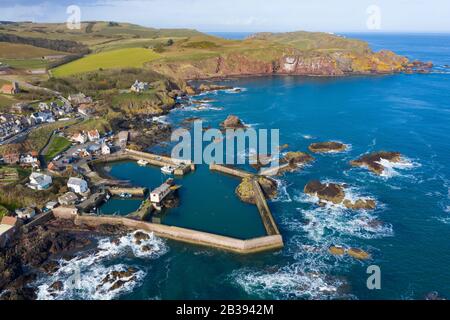 Aerial view of small fishing village and harbour of St Abbs on North Sea coast in Scottish Borders, Scotland, UK