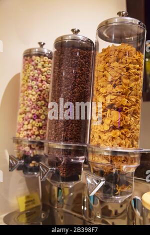 Selective Focused Variety of Breakfast Cereals Morning Meal; Crisp Dark Chocolate, Corn Flakes and Fruit Loops in Cereal Glass Jar Dispensers. Nutriti Stock Photo