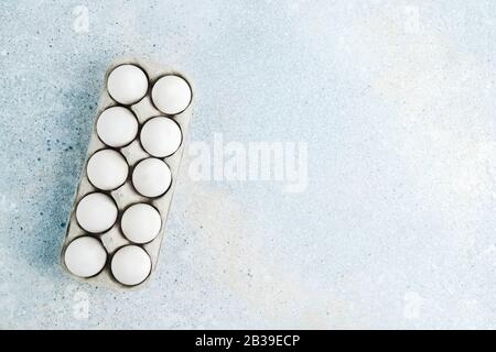 Box with white eggs on blue background. Flatlay, copy space Stock Photo