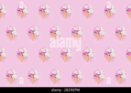 Peonies flowers bouquet in waffle ice cream cone on light pink background. Seamless pattern. Summer concept. Holiday background Stock Photo