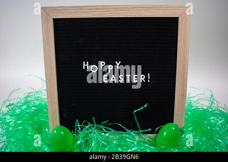A Black Happy Easter Sign With White Letters, Easter Grass, and Easter Eggs Stock Photo
