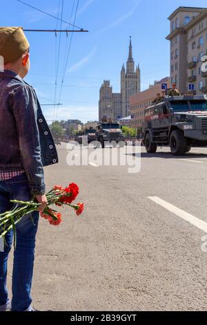 MOSCOW, RUSSIA- MAY 07, 2017: A boy with flowers with hand meet military parade near the Kremlin, Moscow, Russia Stock Photo