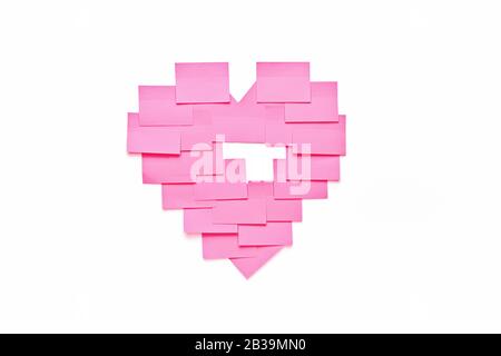 Blank pink sticky notes stick to white wall in heart shape. Valentine day concept in office Stock Photo