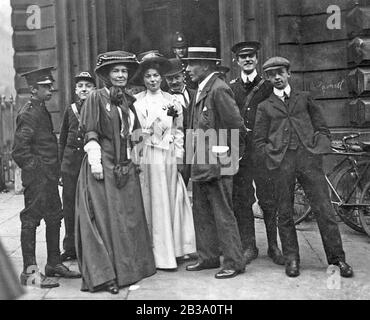 CHRISTABEL PANKHURST (1880-1958) in white with the Emmeline Pethick-Lawrence and her husband outside Bow Street Magistrates Court during the Rush Trial, 14 October 1908. She was convicted the following year.
