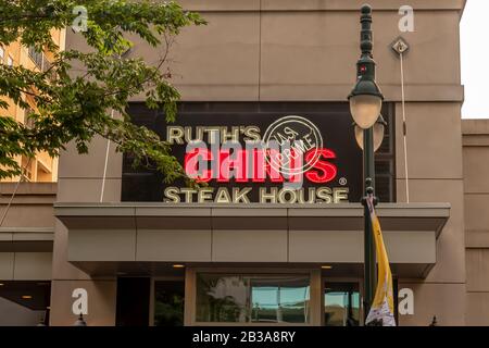 Charlotte, NC/USA - May 26, 2019: Medium closeup of 'Ruth's Chris' steak house facade showing brand above entrance with lamppost and tree branches. Stock Photo