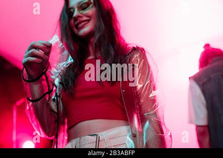 smiling girl holding plastic zipper bag with drugs in nightclub Stock Photo