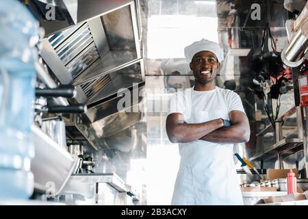 selective focus of happy african american chef standing with crossed arms in food truck Stock Photo