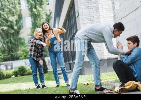 african american boy in hoodie and jeans bulling boy and teenager shooting it and pointing with fingers Stock Photo