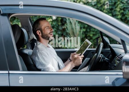 happy bearded man sitting in car and using digital tablet Stock Photo