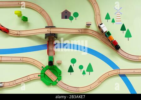 Children's wooden railway with a steam locomotive, top view. A painted landscape with a river , a toy railway with a crossing, a bridge and a road jun Stock Photo