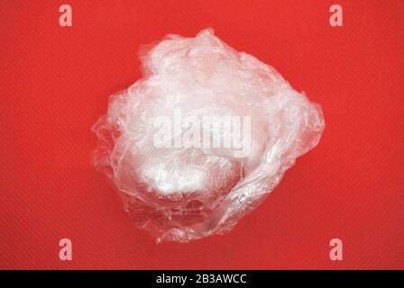 Crushed white clear transparent polyethylene plastic bag on a red background Stock Photo