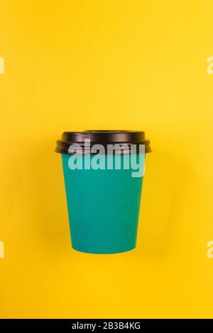 Good morning wake up awake concept. Simply flat lay design blue paper coffee cup isolated on yellow colorful trendy background. Stock Photo