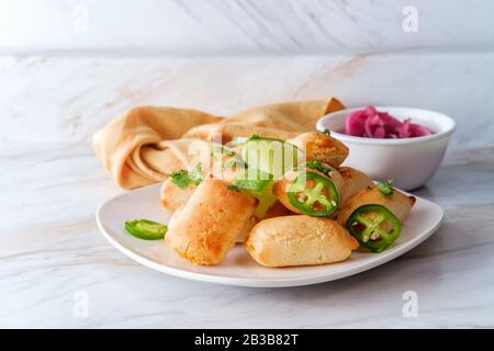 Mexican mini beef empanada appetizer served with preserved red onion pickles Stock Photo