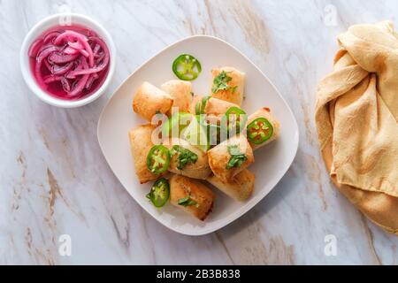 Mexican mini beef empanada appetizer served with preserved red onion pickles Stock Photo
