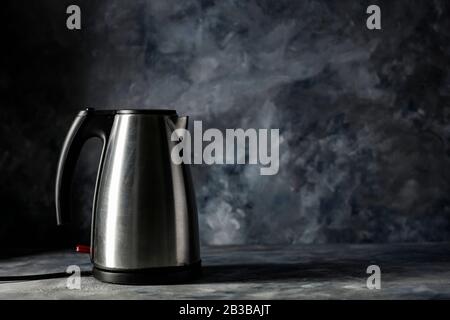 Electric kettle and dark mood wall background. Copy space for your decoration and dark shadows on wall. Stock Photo