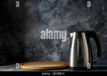 Electric kettle and dark mood wall background. Copy space for your decoration and dark shadows on wall. Stock Photo