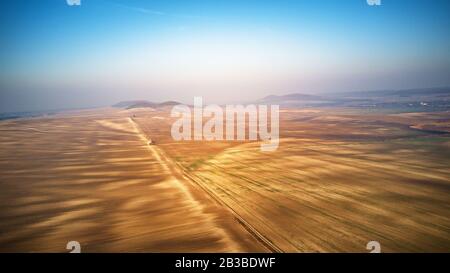 Aerial view of ploughed agricultural field in perspective, high angle view of arable land. Dirt road through the fields. Cultivated land on hills of P Stock Photo