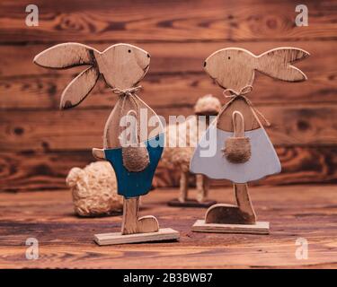 couple of wooden easter bunnies near toy sheep on old wood background Stock Photo