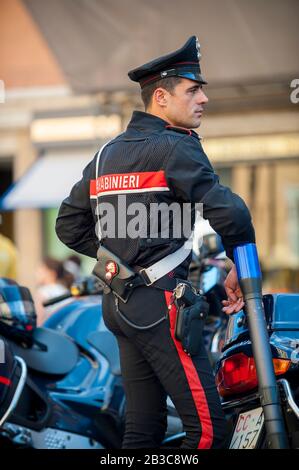 ROME - MAY 12, 2012: Italian police officer stands in uniform leaning against his motorcycle at the Piazza di Spagna. Stock Photo