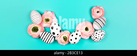 Creative graphic hand-painted eggs and ranunculus flowers on blue pastel background. Easter concept. Place for text. Stock Photo
