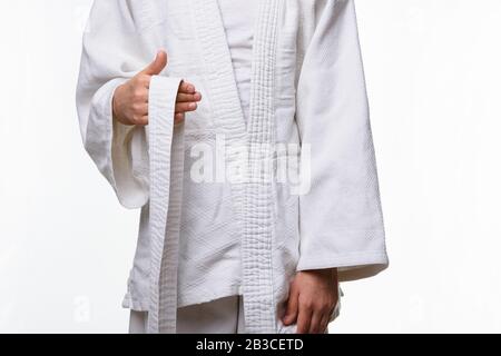 Stages of correct tying of the belt by a teenager on a sports kimono, step one Stock Photo