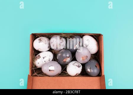 Silver painted decorative eggs in wooden box on pastel blue background. Easter concept. Place for text. Stock Photo