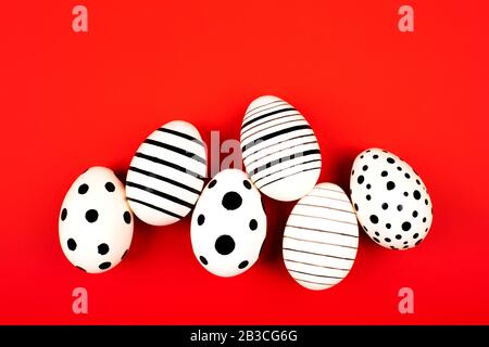Different graphic hand-painted eggs on bright red background. Easter concept. Flat lay style. Stock Photo