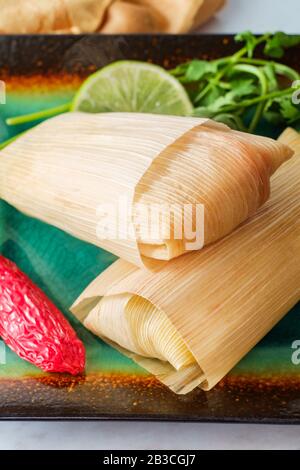 Mexican steamed chili and cheese masa tamales wrapped in corn husk Stock Photo