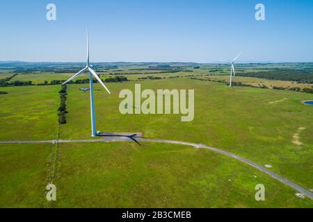 Two wind turbines among green grazelands in the countryside - aerial landscape Stock Photo