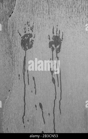 Scary blood dripping hand marks on a wall in black and white Stock Photo