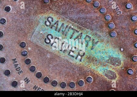 A close up view of a the brown-red and green rusted cover of a sanitation department. Stock Photo