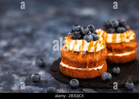 Homemade carrot individual cakes with caramel sauce, cream cheese frosting and fresh blueberries Stock Photo
