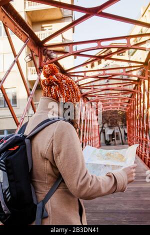 woman tourist looking at the map on a bridge of european city, travel to Europe Stock Photo