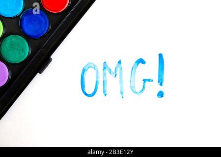 Handwritten OMG text with brush and watercolor paints on white background. Oh my god. Stock Photo