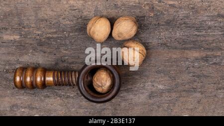 Organic walnuts with nut cracker on a wooden table, wooden background. Crushing, healthy. Stock Photo