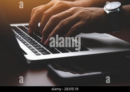 Closeup of a businessman hands working and typing on laptop keyboard Stock Photo