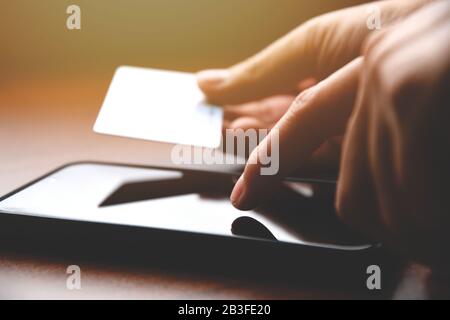 Closeup male hands holding credit card and using mobile smart phone for online shopping Stock Photo