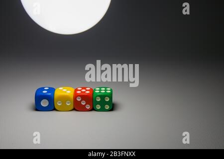 color dice with numbers on grey background with light from a lamp Stock Photo