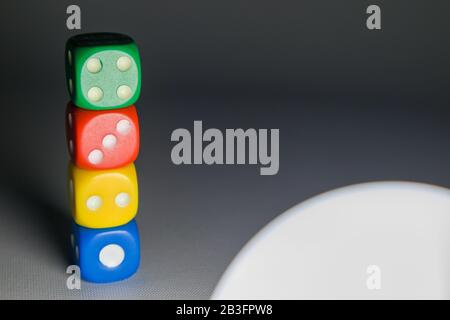 four color dice on grey background with light from a lamp Stock Photo