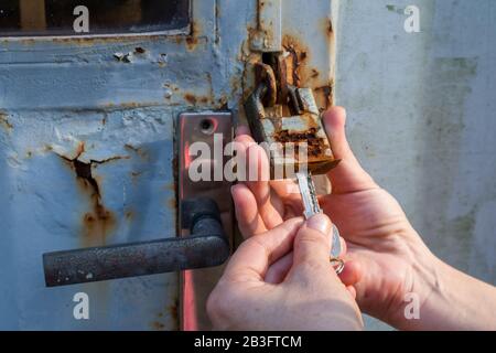Close up hands trying to unlock an old and rusty padlock  Stock Photo