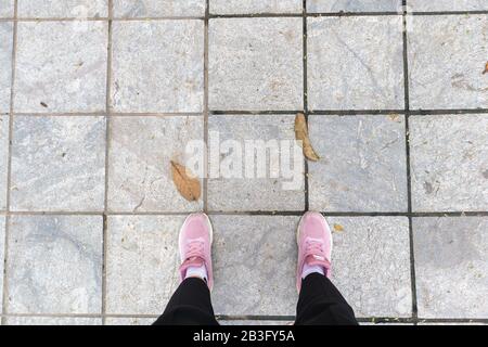 Pink snickers with legs on a grey street with two leaf Stock Photo