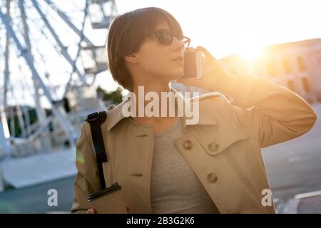 Fashion teen girl talking on mobile phone walking on city street. Stock Photo