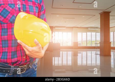 Engineer check in decorate Interior room and hand holding yellow helmet. concept construction background Stock Photo