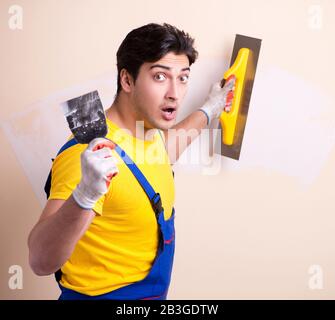 The young contractor employee applying plaster on wall Stock Photo
