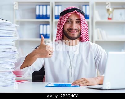 Arab businessman working in the office doing paperwork with a pile of papers Stock Photo