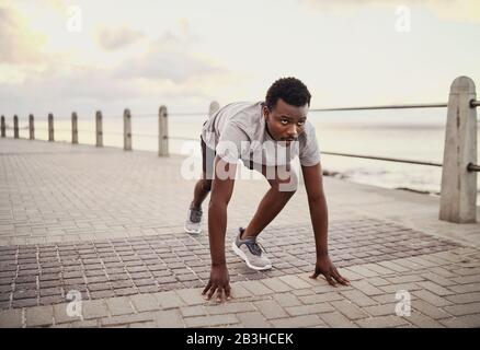 Young male athlete ready for run at workout training session on seaside promenade in the morning Stock Photo